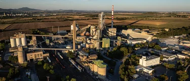 Letecký pohled na cementárnu Holcim v Čížkovicích v podvečerním světle, v pozadí kopce Českého středohoří